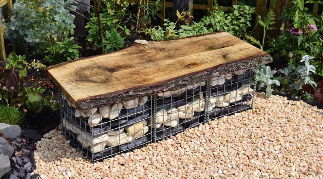Steel basket made into a seat filled with cream cobbles and plum slate paddlestones in a layered effect.
