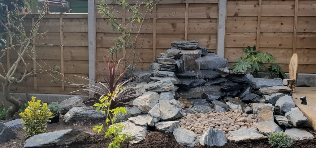 Charcoal Slate Rockery used in a water feature. with Beige pebbles.