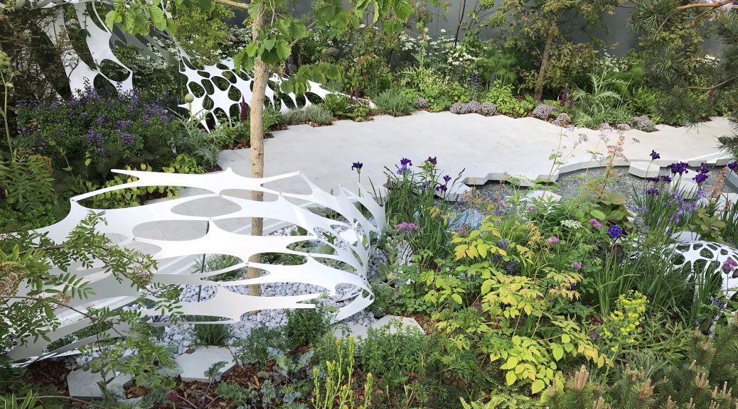The Manchester Garden at RHS Chelsea with lots of greenery, grey paving and a white woven sculpture.