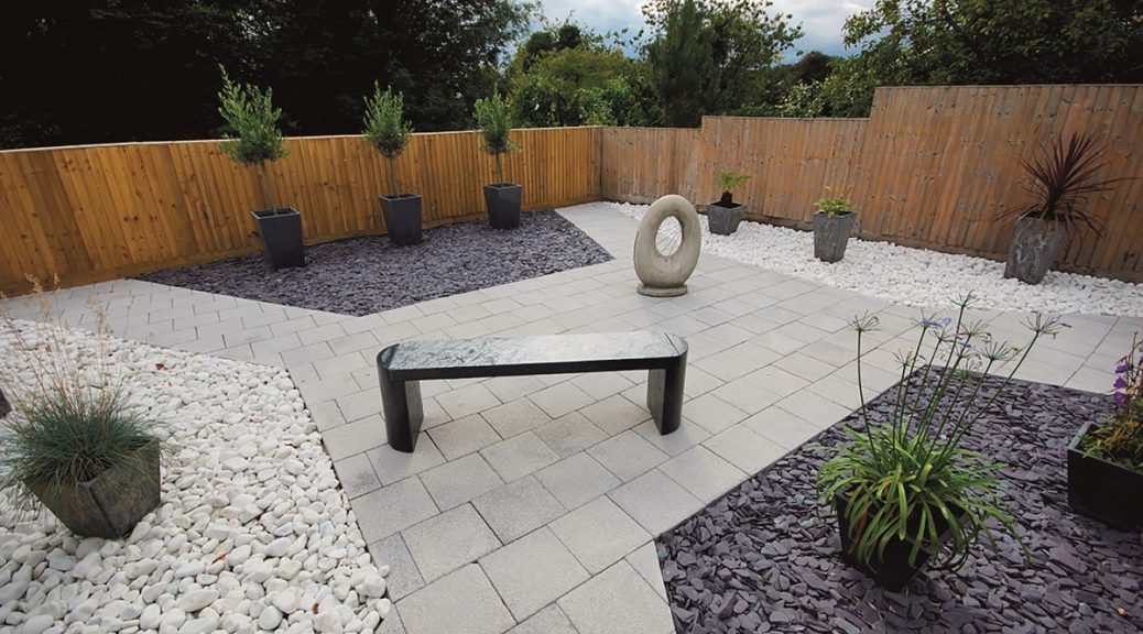 Garden with pale grey paving and white cobbles along with p[um slate paddlestones