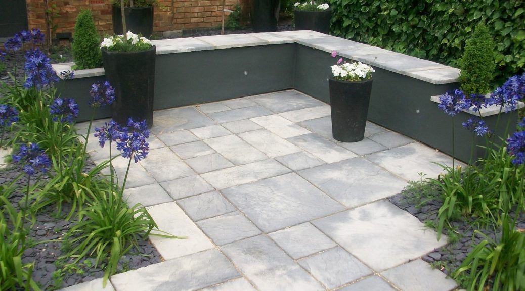 Garden with Bronte Weathered stone paving surrounded by a grey wall.